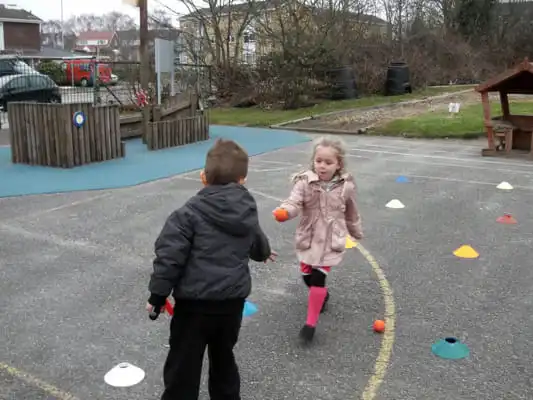 Image of Tri-Golf Session - Little girl passing a ball to a boy.